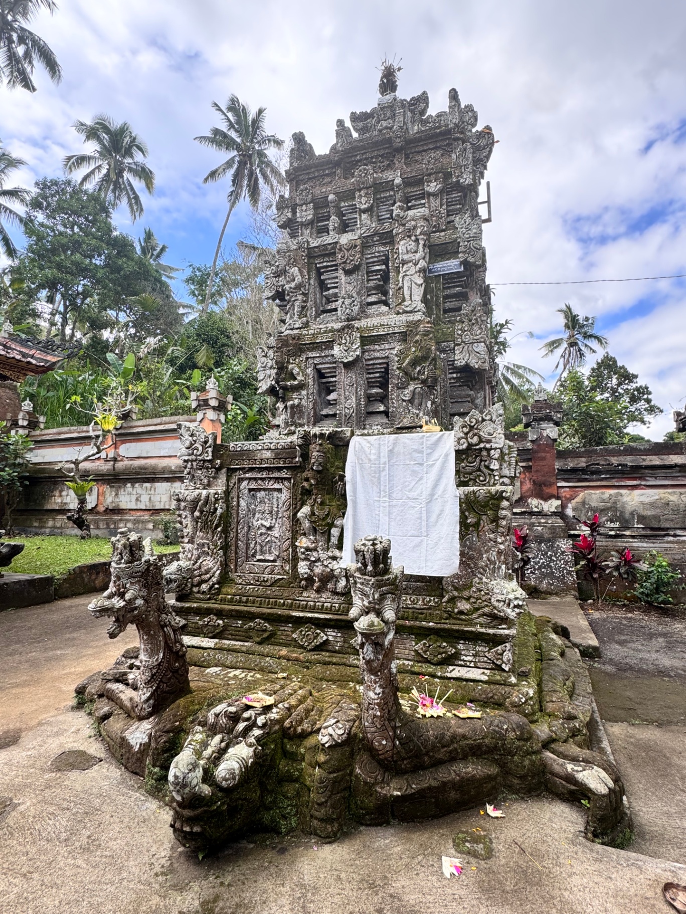 Carved shrine with dragon guardians and a hanging white cloth offering