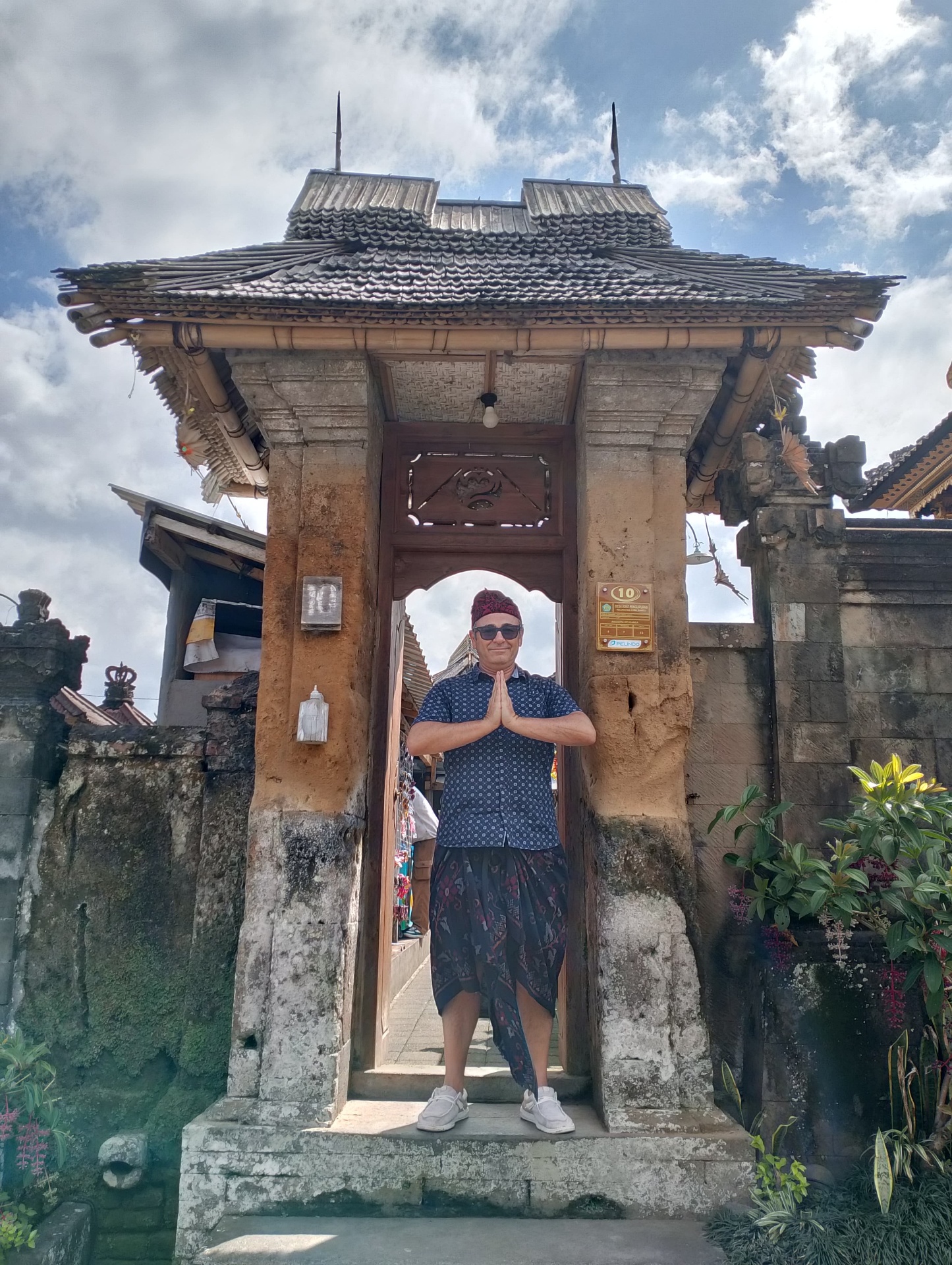 Luis at a village candi bentar (split gate) in Ubud, dressed in sarong and udeng