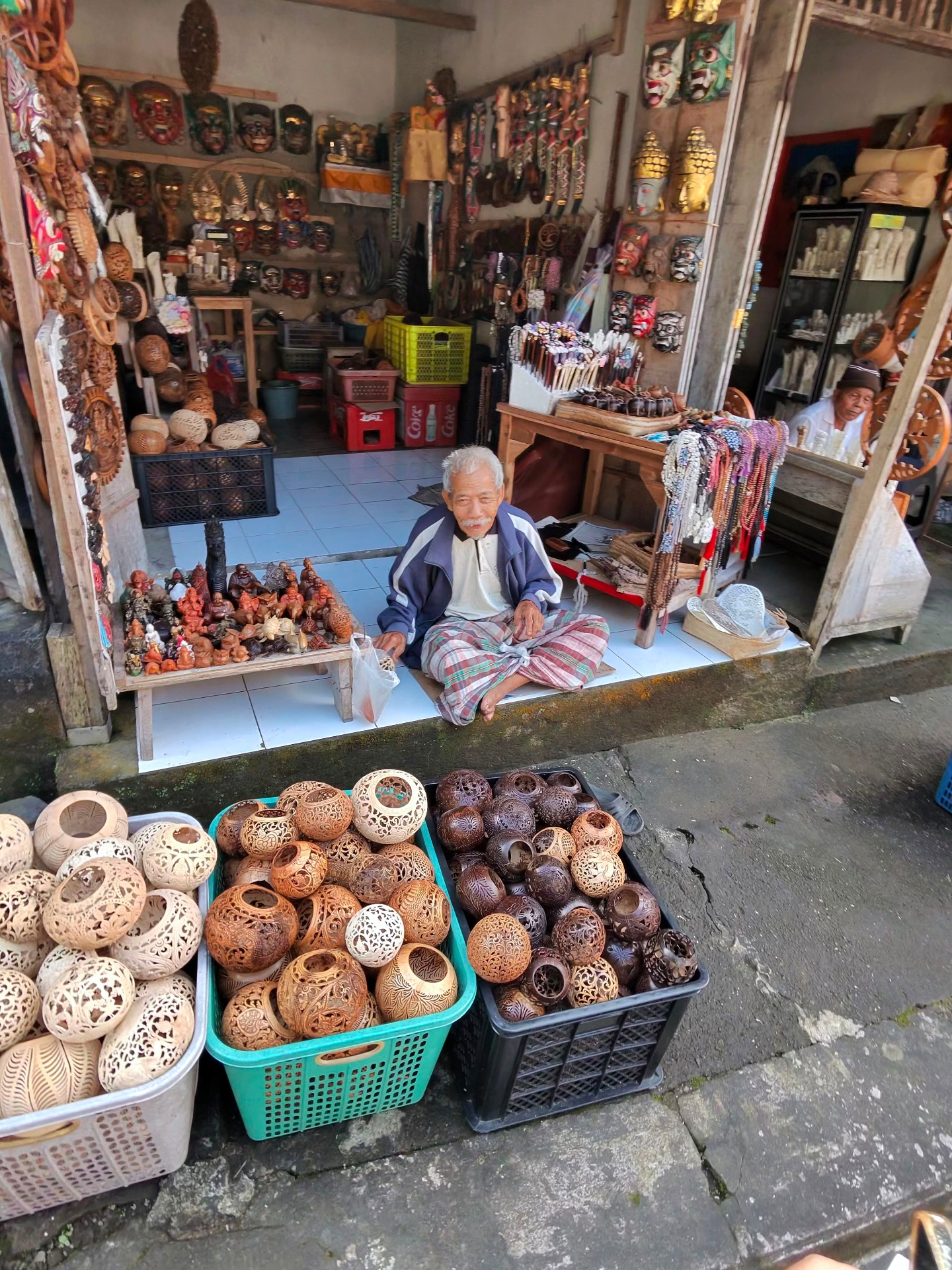 Elder artisan in an Ubud mask and carved-coconut shop