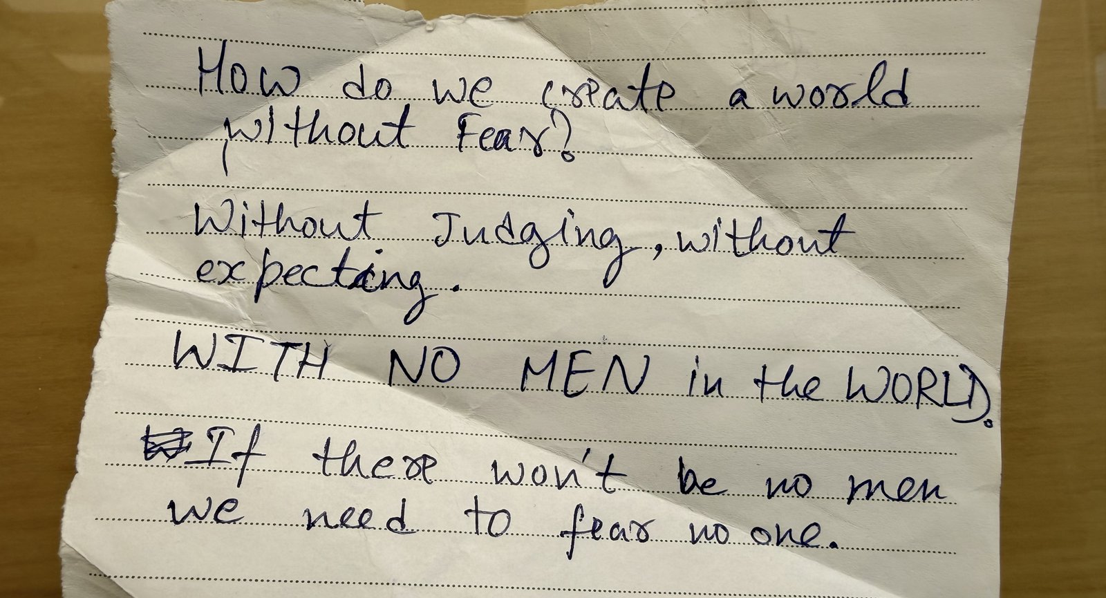 A handwritten page torn from a student's notebook, ending in capital letters: WITH NO MEN in the WORLD.